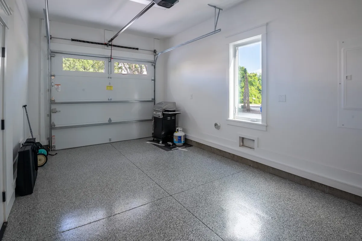 A spacious, well-organized garage with a clean floor, natural light streaming through a window, and a functional layout for parking, storage, or working on hobbies.