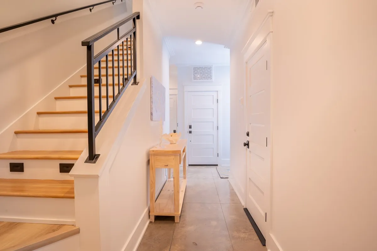 This image features a stylish entryway with a staircase, console table, and doors leading to other parts of the home. The space is bathed in natural light, creating a welcoming atmosphere ideal for greeting guests or beginning a day of exploration.