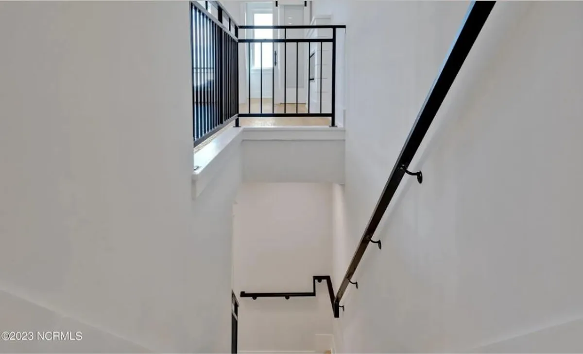 This image features a modern, airy staircase with natural light streaming from the upper level. The open railing and gathering space at the top suggest movement, connection, and the potential for shared moments, echoing the transition between everyday life and vacation relaxation.