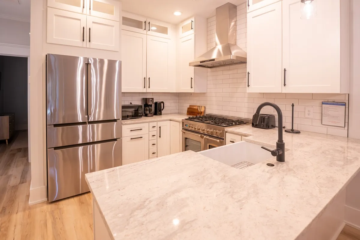 A contemporary kitchen with stainless steel appliances, granite countertops, a gas range stove, and under-cabinet lighting. The space is both functional and stylish, inviting guests to cook, gather, and entertain.