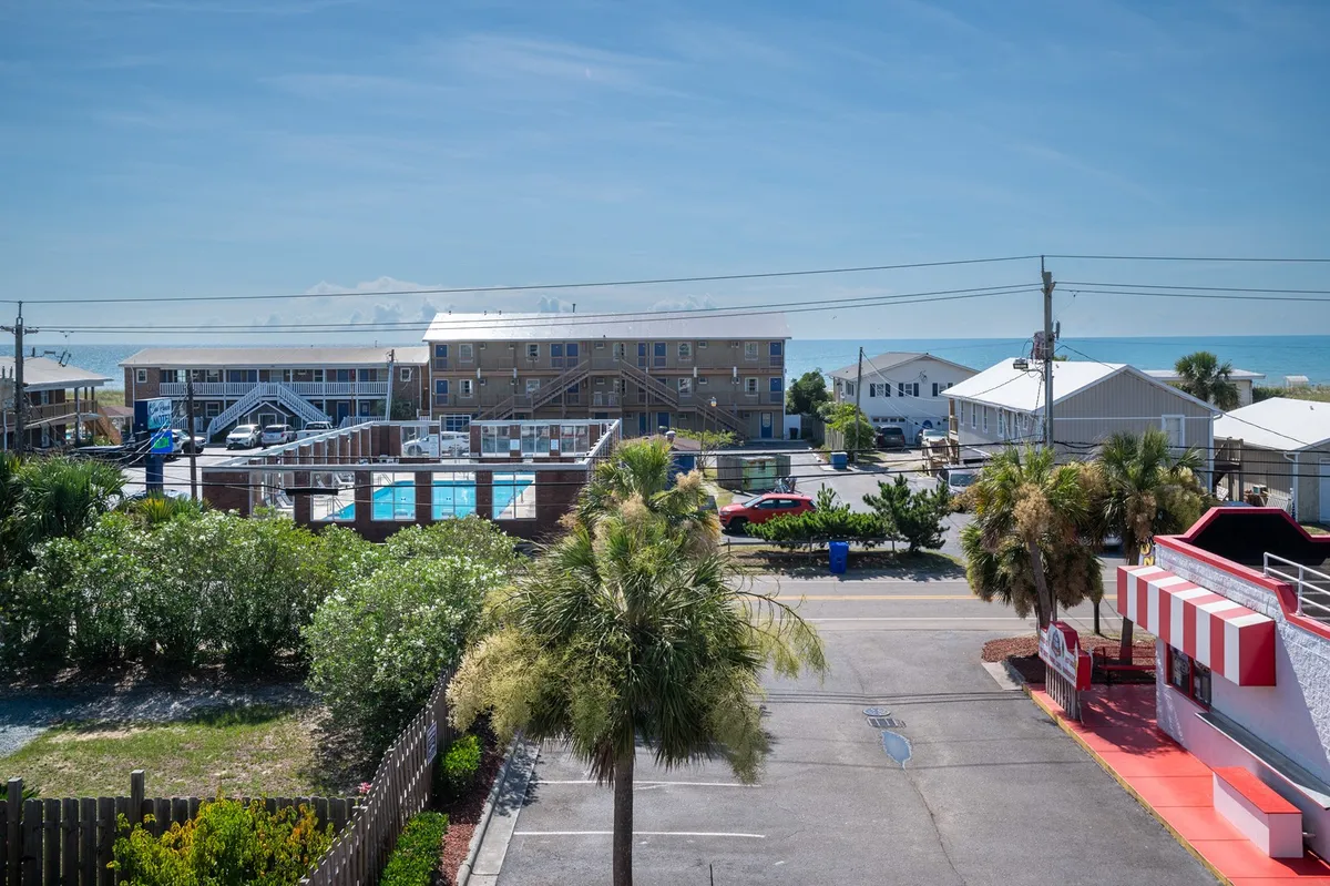 A wide exterior scene showcasing a sparkling swimming pool, palm trees, sandy beach, and the ocean, with modern hotel buildings in the background. The image conveys a vibrant vacation atmosphere, highlighting both relaxation and opportunities for seaside activity.